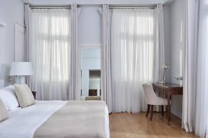 a bedroom with a white bed and a desk and a desk at Poseidonion Grand Hotel in Spetses