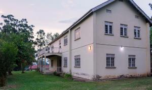 a large white house with a grass yard at Sunrise Apartments Hotel Fort Portal in Fort Portal
