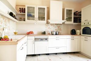a white kitchen with white cabinets and fruits on the counter at blueline guesthouse in Áyios Dhimítrios