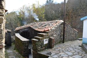 una vieja casa de piedra con humo saliendo de ella en Casa Javali en Chiqueiro