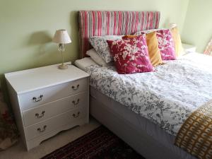 um quarto com uma cama com almofadas cor-de-rosa e uma mesa de cabeceira em UPTHEDOWNS B&B em Sevenoaks