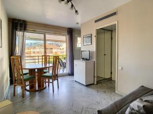 a living room with a table and chairs and a kitchen at Cozy Apartment sea view Air Cond in Golfe-Juan