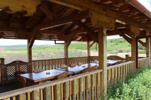 a wooden pavilion with tables and chairs on a deck at Ardelean Lake House in Doştat