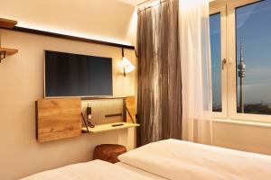 a bedroom with a television and a bed at H2 Hotel München Olympiapark in Munich