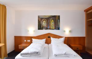 a bedroom with two beds and a painting on the wall at Palazzo Hotel - direkt im Zentrum in Mönchengladbach