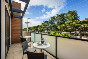 a patio with a white table and chairs on a balcony at Oceanic on Thompson Apartments in Cowes