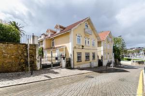 ein großes Haus auf einer Straße mit einem Zaun in der Unterkunft Casa do Tamariz, XIX century Beach House in Estoril