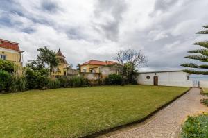un cortile con una casa e un prato di Casa do Tamariz, XIX century Beach House a Estoril
