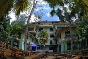 a hotel with tables and palm trees in front of it at Borneo Tropical Rainforest Resort in Kampong Butir