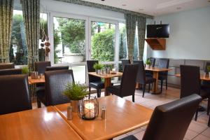 a restaurant with wooden tables and chairs and windows at Palazzo Hotel - direkt im Zentrum in Mönchengladbach