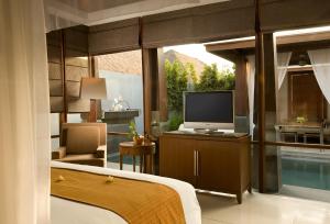 een slaapkamer met een televisie en een kamer met een zwembad bij The Kayana in Seminyak