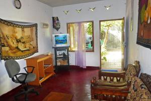 uma sala de estar com uma televisão, uma cadeira e uma secretária em Grace Homestay em Negombo