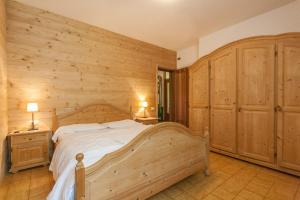 - une chambre avec un grand lit et des murs en bois dans l'établissement Villa Licia, à Falcade