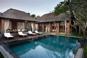 a swimming pool in front of a villa at The Kayana in Seminyak
