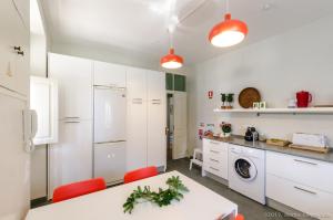a kitchen with white cabinets and a table and red chairs at Casa do Tamariz, XIX century Beach House in Estoril