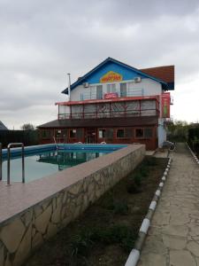 a building with a swimming pool in front of a building at Pensiunea Harttas in Maliuc