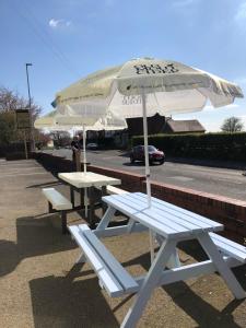 twee picknicktafels en een paraplu op straat bij The Glazebury bar and restaurant with accommodation in Glazebury