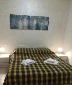 Una cama amarilla y azul a cuadros con dos toallas. en Residence La Madonnina, en Peschiera del Garda