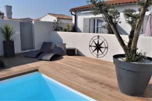 a patio with a pool and a tree in a pot at Fleur de Ré in Loix