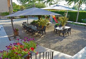 een groep tafels en stoelen met parasols en bloemen bij Agriturismo Argaland in Parma