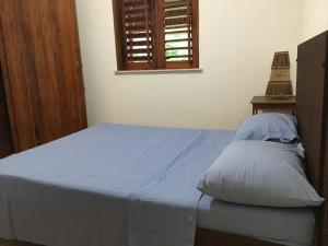 sypialnia z łóżkiem z niebieską pościelą i oknem w obiekcie Os Navegantes A w mieście Guajiru
