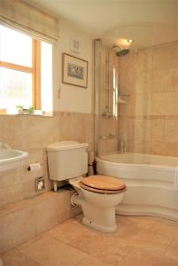 a bathroom with a toilet and a tub and a sink at Cuddy's Croft in Chatton
