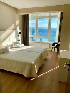 a bedroom with a large bed with a view of the ocean at Hotel La Cruz in Muxia