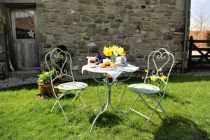 a table and chairs in the grass with a table and flowers at Cuddy's Croft in Chatton