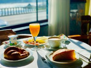 a table with plates of food and a cup of orange juice at Hotel La Cruz in Muxia