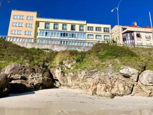 a building on top of a cliff next to a beach at Hotel La Cruz in Muxia
