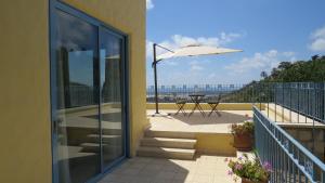 a balcony with a table and an umbrella at ARTSEA Studio Apartment with sea view in ‘En Hod