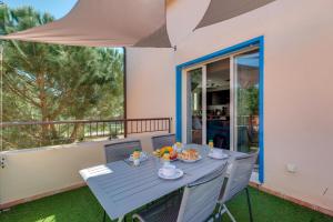 einen blauen Tisch und Stühle auf einem Balkon mit Sonnenschirm in der Unterkunft Terrazza SOLI MARE in Belgodère