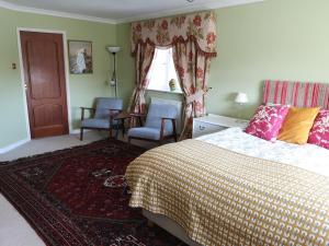 a bedroom with a bed and two chairs and a window at UPTHEDOWNS B&B in Sevenoaks