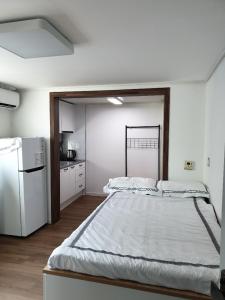 a bedroom with a large bed and a refrigerator at DAGA59 Guesthouse in Daejeon