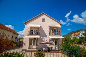 a white house with an umbrella in front of it at Belane Apartments in Tivat