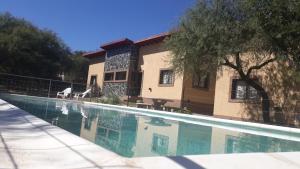 a house with a swimming pool in front of a building at Cabañas Corazon de Maria in Merlo