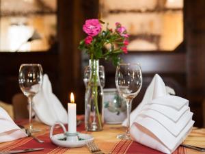 a table with a candle and a vase with pink flowers at Landhotel Zum Hammer in Tannenberg