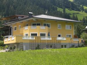 Casa amarilla con balcones blancos en un campo en Traum-Ferienwohnungen Wechselberger Schwendau en Schwendau