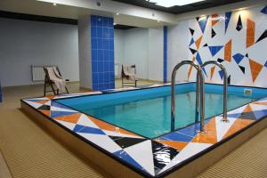 una piscina en una habitación con una pared de azulejos en Topaz Hotel, en Kámensk-Uralsky