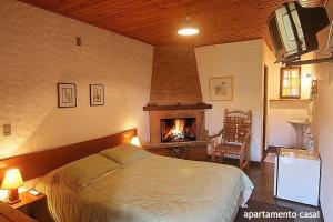 1 dormitorio con 1 cama y chimenea en Pousada da Trilha, en Monte Verde