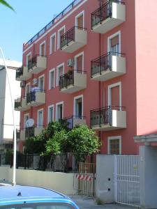 ein rosafarbenes Gebäude mit Balkonen und einem Auto, das vor der Tür geparkt ist in der Unterkunft Anania in Cagliari