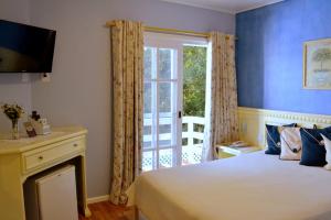 1 dormitorio con cama y ventana grande en Pousada Jardim Azul, en Canela