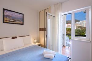 a white bedroom with a bed and a balcony at Apartment Ivanovic Family in Becici