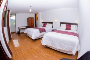 2 bedden in een hotelkamer met houten vloeren bij La Casa de Los Balcones in Chachapoyas