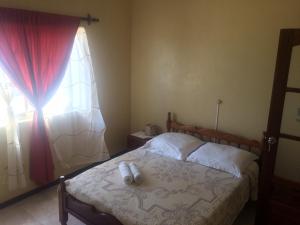 1 dormitorio con 1 cama con cortina roja y ventana en Sissi's B&B en Ponta do Sol