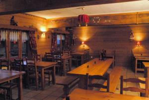 an empty restaurant with wooden tables and chairs at Hôtel Chalet Le Caribou in Les Saisies