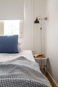 Dormitorio con cama con almohada azul y lámpara en Torget Apartment Länsiportti, en Pori