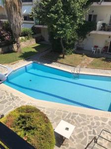 a large blue swimming pool in front of a house at Harmony Apartment in Kallithea Halkidikis