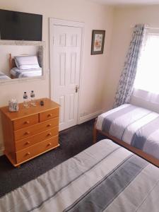 a bedroom with two beds and a dresser and a window at Billycan Guest Rooms in Kilkenny
