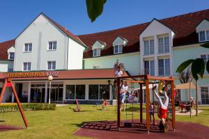 eine Gruppe von Kindern, die auf einem Spielplatz vor einem Gebäude spielen in der Unterkunft Thermenhotel Kurz in Lutzmannsburg